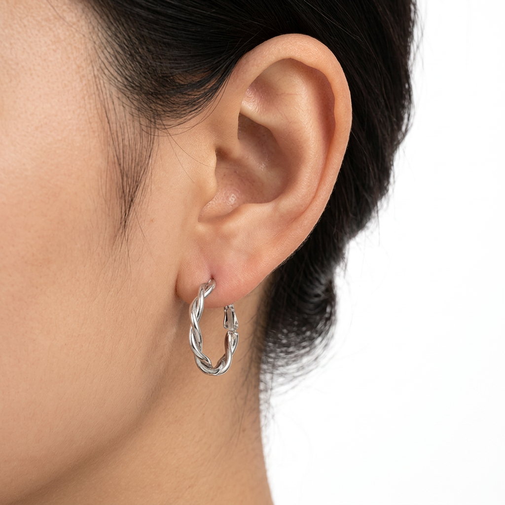 Srebrny kolczyk z falującym konturem na uchu modelki na białym tle